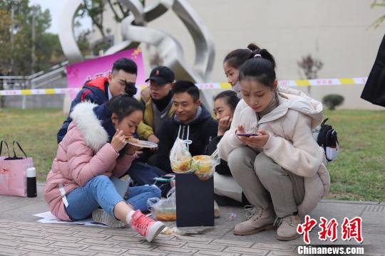 等候考试的学生坐在地上吃饭。　钟欣 摄